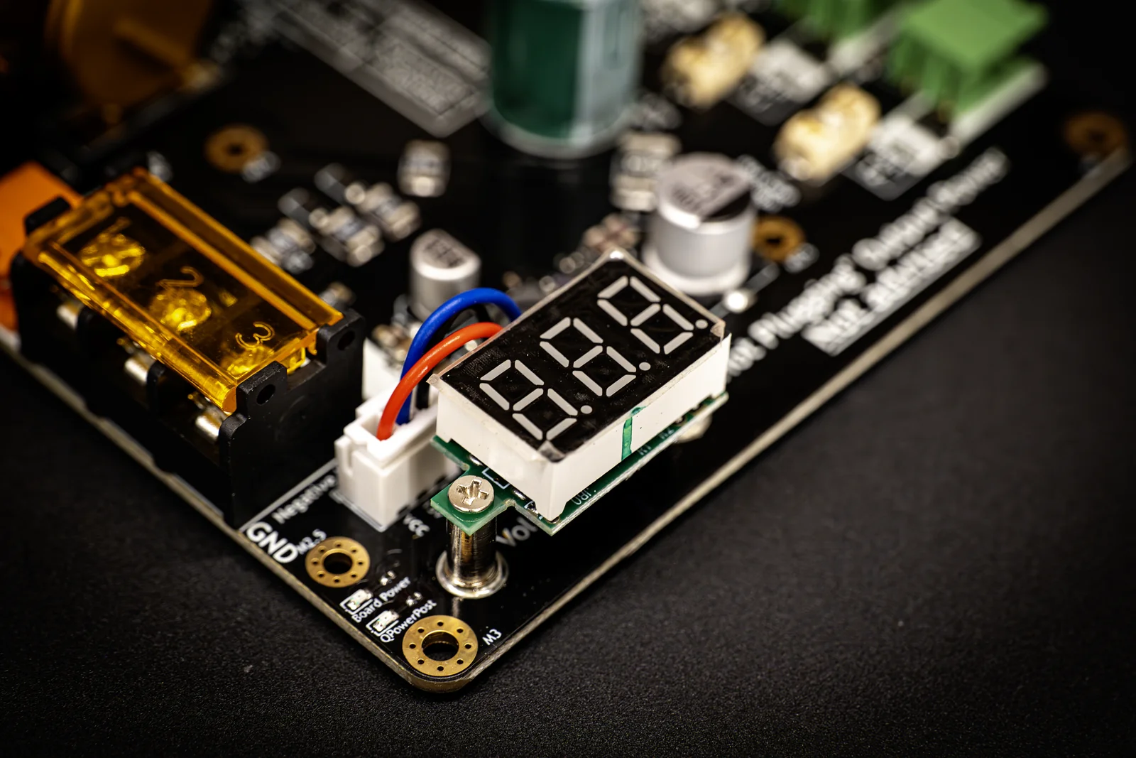 Red 7-segment voltage display lit on a black Power-5HV powerboard next to brass busbar terminals