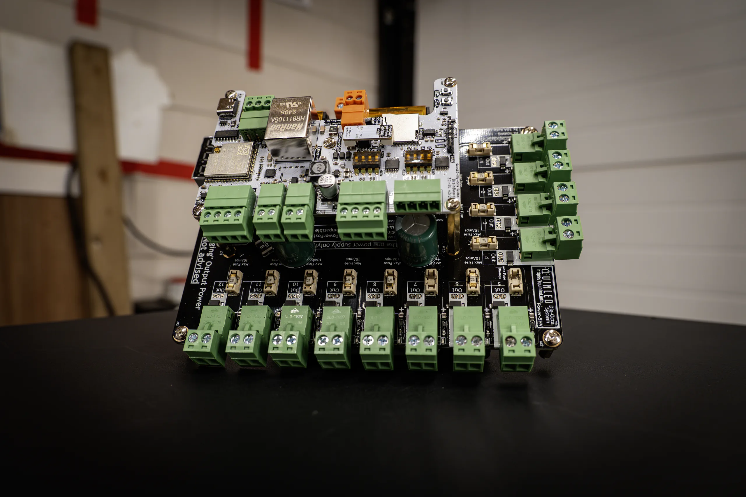 QuinLED Dig-Octa Power-5HV stack with a white Brainboard-32-8L on top, green pluggable terminals and gold auto-reset fuses on black PCB