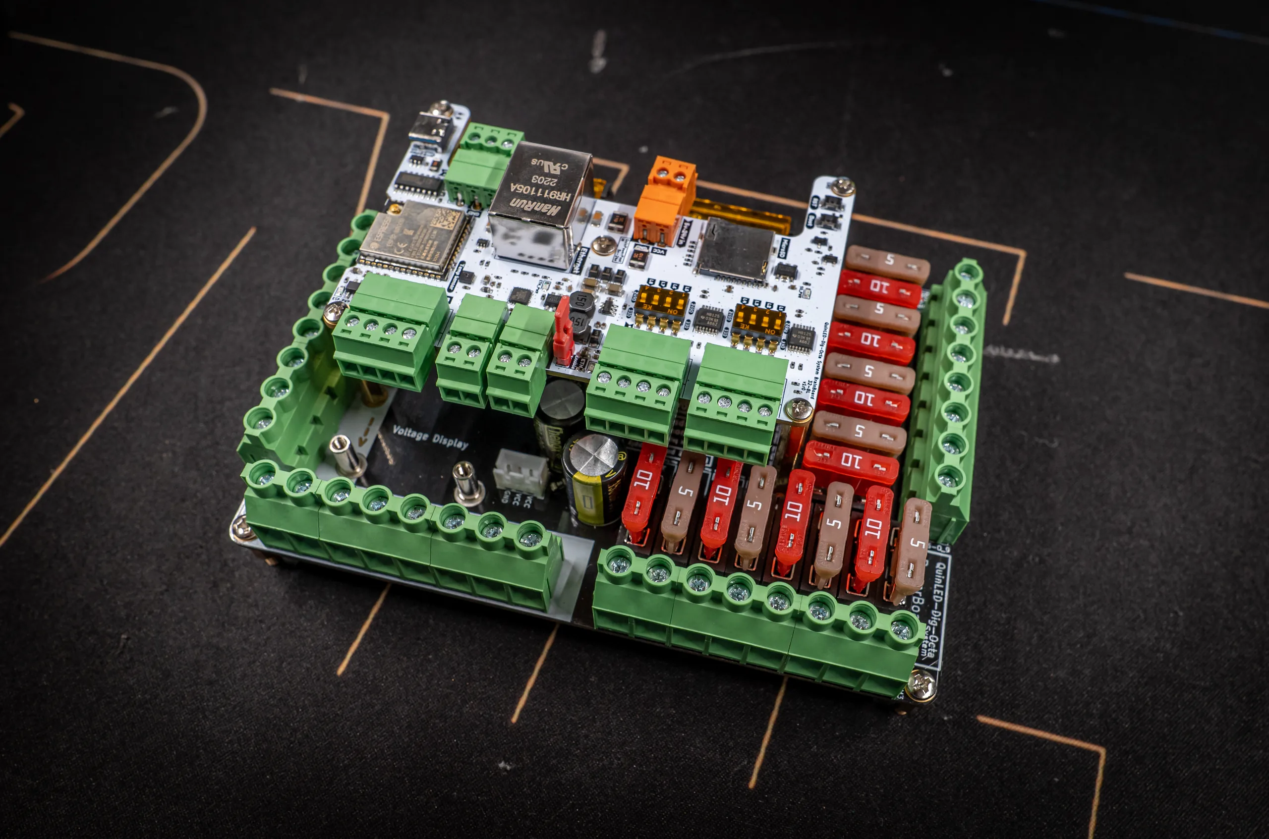 Assembled QuinLED Dig-Octa stack: white Brainboard-32-8L on a black Power-7 ringed by 16 green screw terminals and rows of red and tan blade fuses