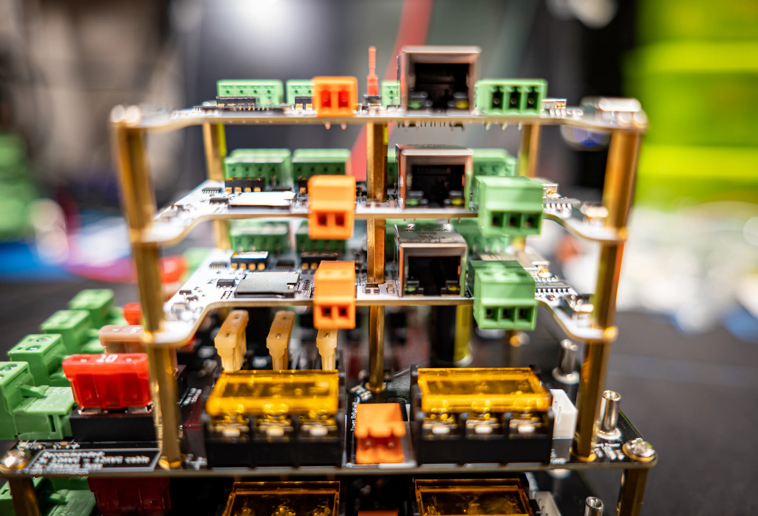 Three QuinLED Dig-Octa brainboards stacked on brass QPowerPost standoffs above a powerboard, shallow depth of field